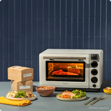 Tovala smart oven roasting salmon on a countertop beside Blueprint Certified Longevity Meals boxes and plated meals