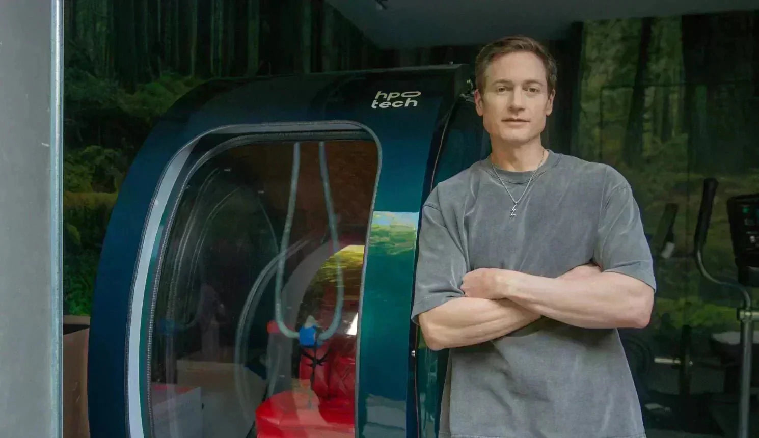 Bryan Johnson standing in front of a hyperbaric oxygen therapy (HBOT) chamber.