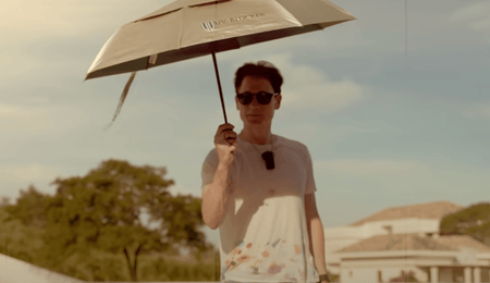 Bryan Johnson outdoors holding a UV-blocking umbrella and wearing sunglasses for sun protection.