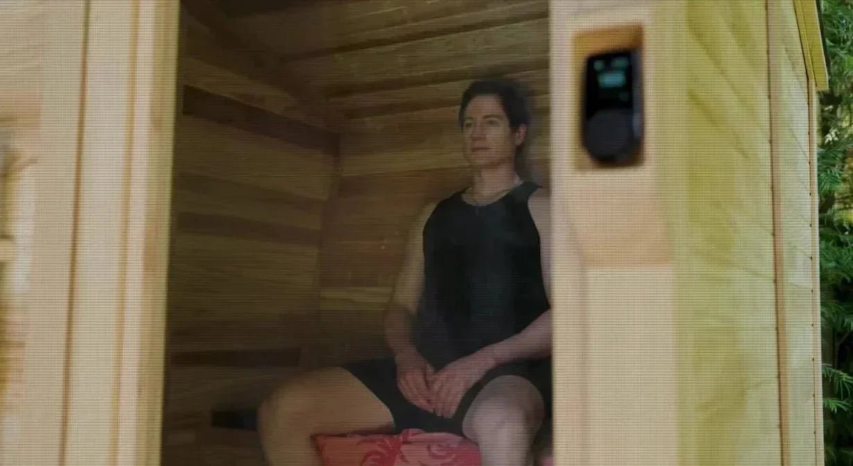 Bryan Johnson sitting inside a sauna with a digital temperature display visible on the wall.