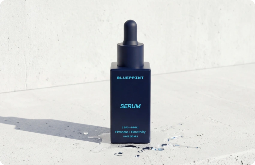 Blue serum bottle with dropper on a light gray background