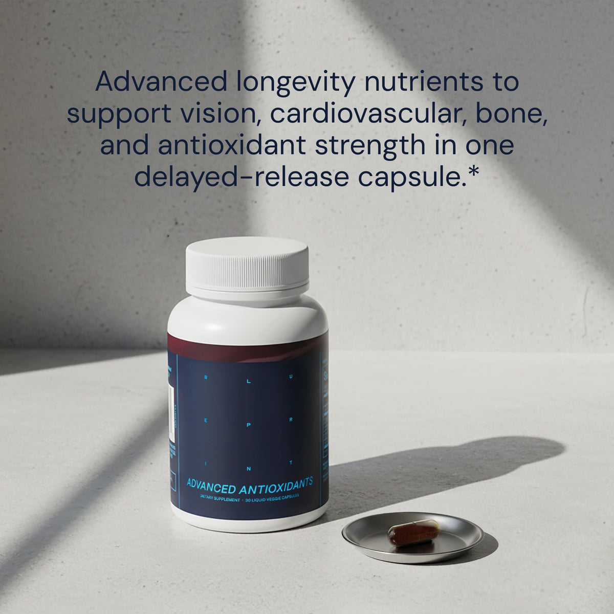 Bottle of 'Advanced Antioxidants' with a pill on a gray surface and text about nutrients.
