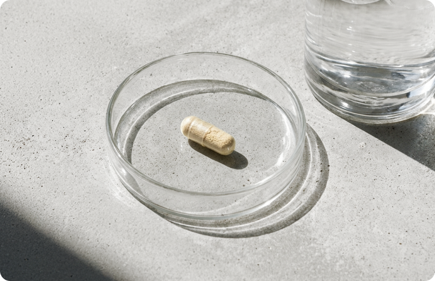 Capsule on a glass plate with a glass of water on a concrete surface