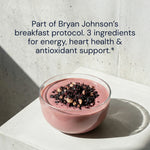 Pink smoothie bowl with toppings on a white surface, text about Bryan Johnson's breakfast protocol.