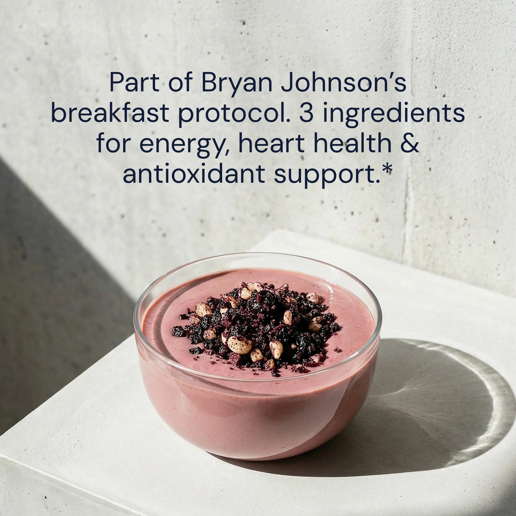 Pink smoothie bowl with toppings on a white surface, text about Bryan Johnson's breakfast protocol.