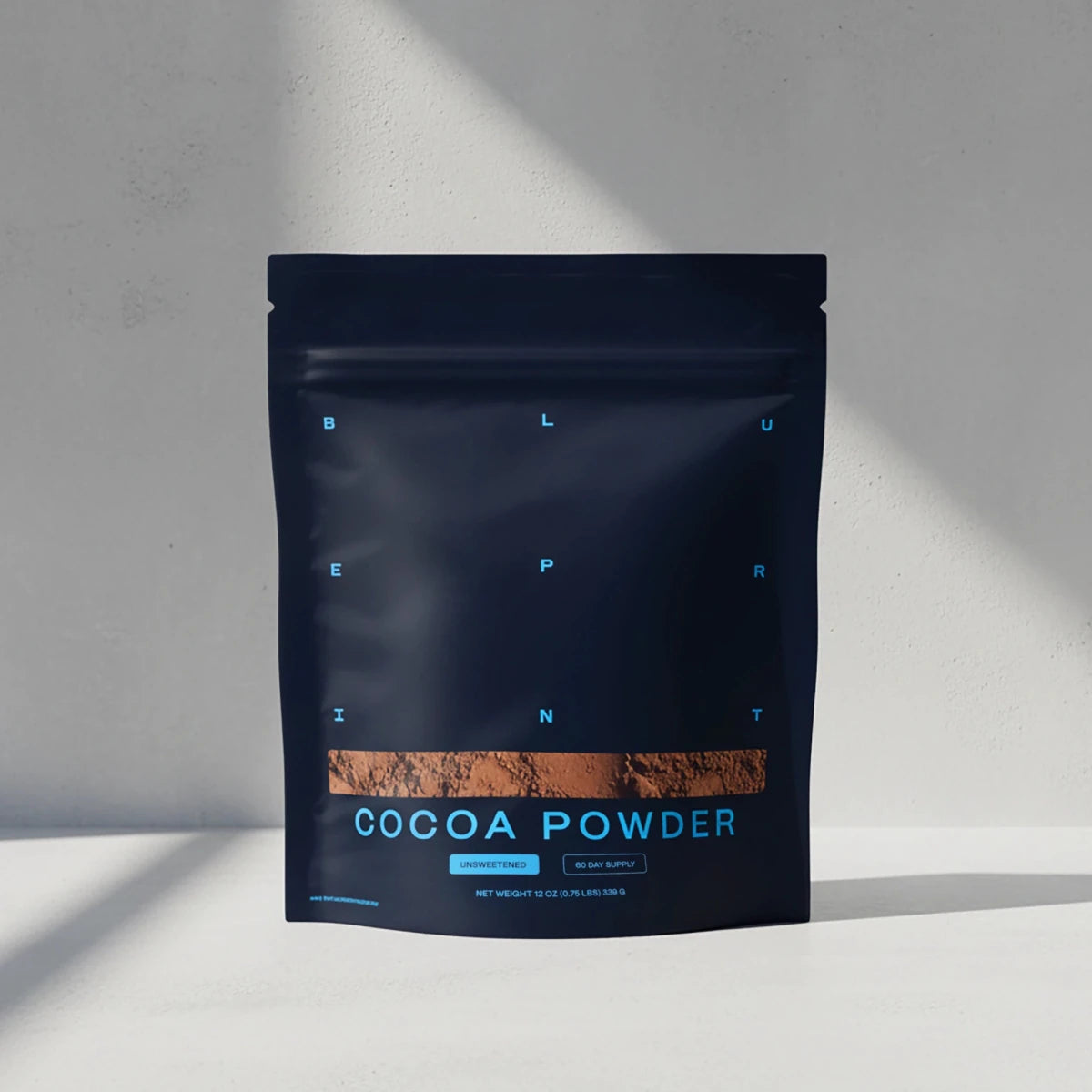 Dark blue package of cocoa powder on a light gray background