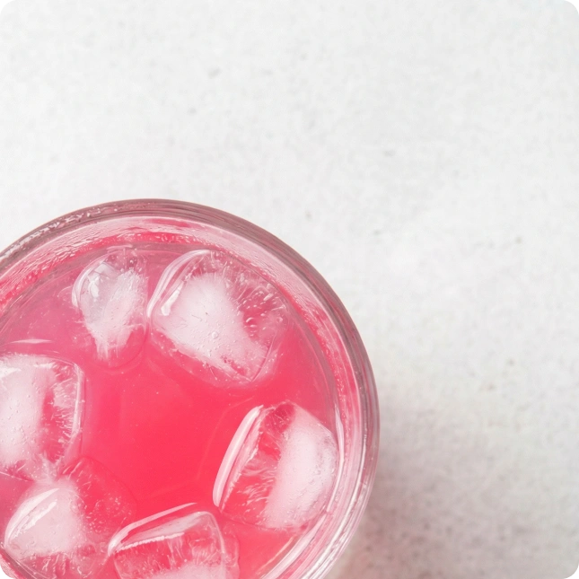 Pink drink with ice cubes in a clear container on a white background