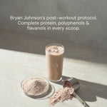 Glass of protein shake with a scoop and container on a light surface, text about Bryan Johnson's post-workout protocol.