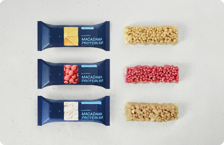 Macadamia protein bars with different flavor options on a white surface
