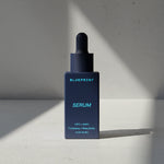 Blue serum bottle with dropper labeled 'Blueprint' on a light gray background