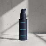 Blue bottle of Blueprint moisturizer on a gray concrete background