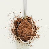 Spoon filled with cocoa powder on a white background
