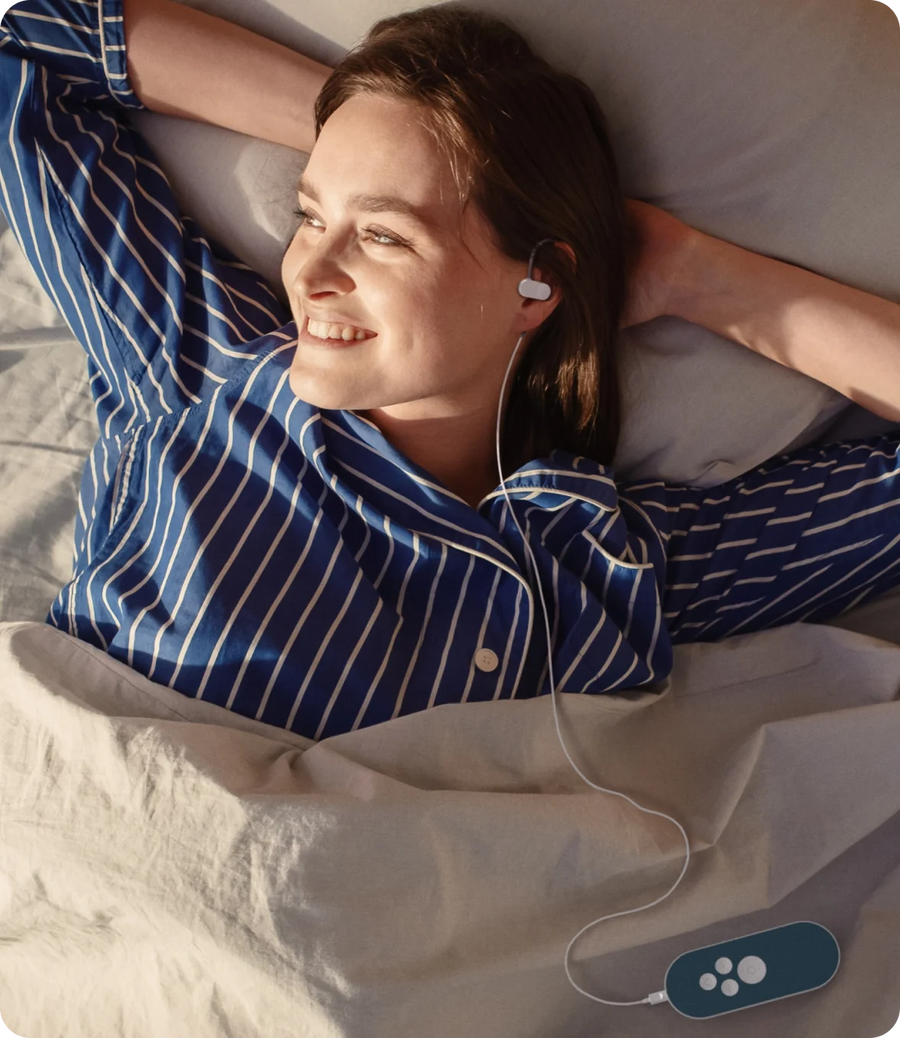 Woman in striped pajamas resting in bed with wired sleep earbuds, Blueprint sleep optimization
