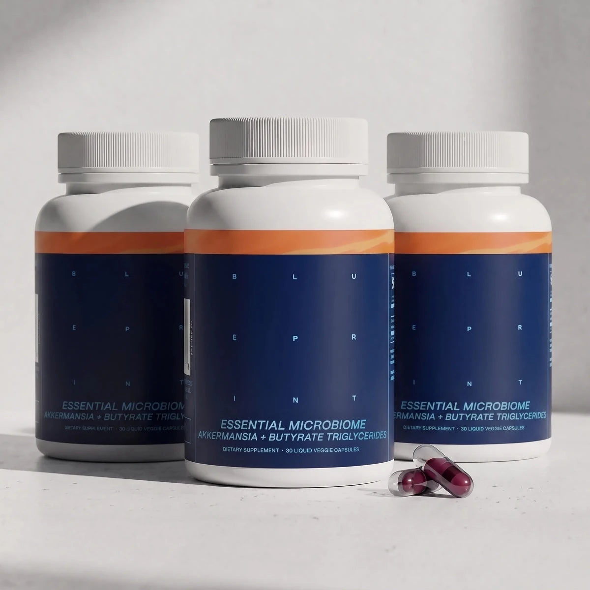 Blueprint Essential Microbiome three-pack with capsules beside the bottles