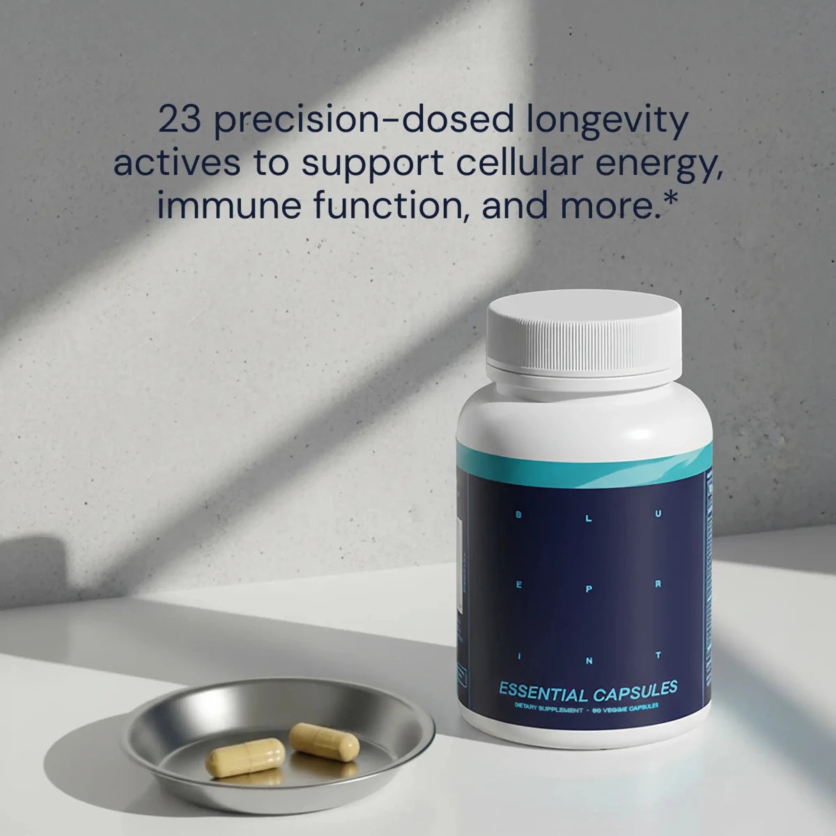 Blueprint Essential Capsules bottle with two capsules in a metal dish — 23 precision-dosed longevity actives