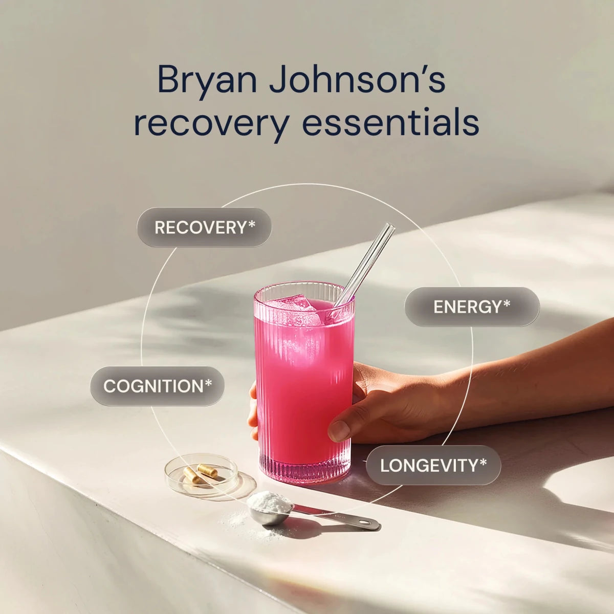 Hand holding a pink drink with text on recovery, energy, cognition, and longevity, branded as Bryan Johnson's recovery essentials.