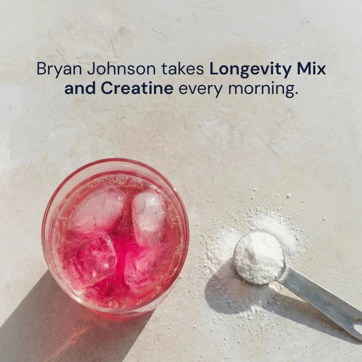 Pink drink with ice and a scoop of powder on a light surface, with text about Bryan Johnson taking Longevity Mix and Creatine.