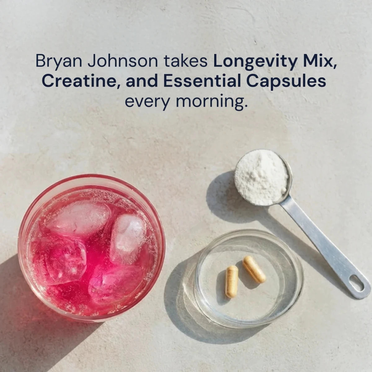 Pink drink with ice, a spoonful of powder, and capsules on a light surface.