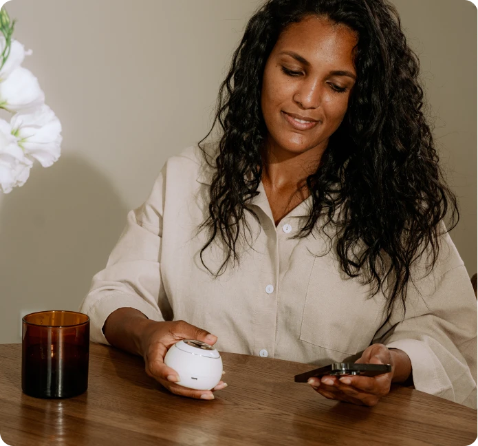 Woman at a table using the Mira hormone monitor and app to track her cycle at home
