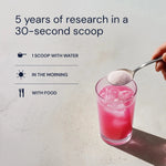 Scooping Blueprint Longevity Mix into a pink drink: 5 years of longevity research in a 30-second scoop