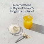 Scoop of Longevity Mix powder beside a yellow citrus drink, a cornerstone of Bryan Johnson's longevity protocol