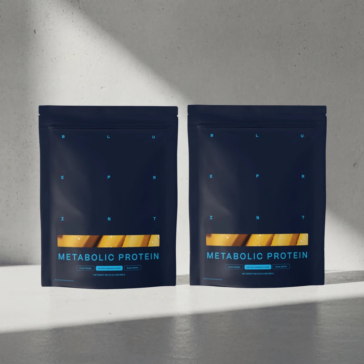 Two packages of Metabolic Protein on a gray surface with a light gray background 