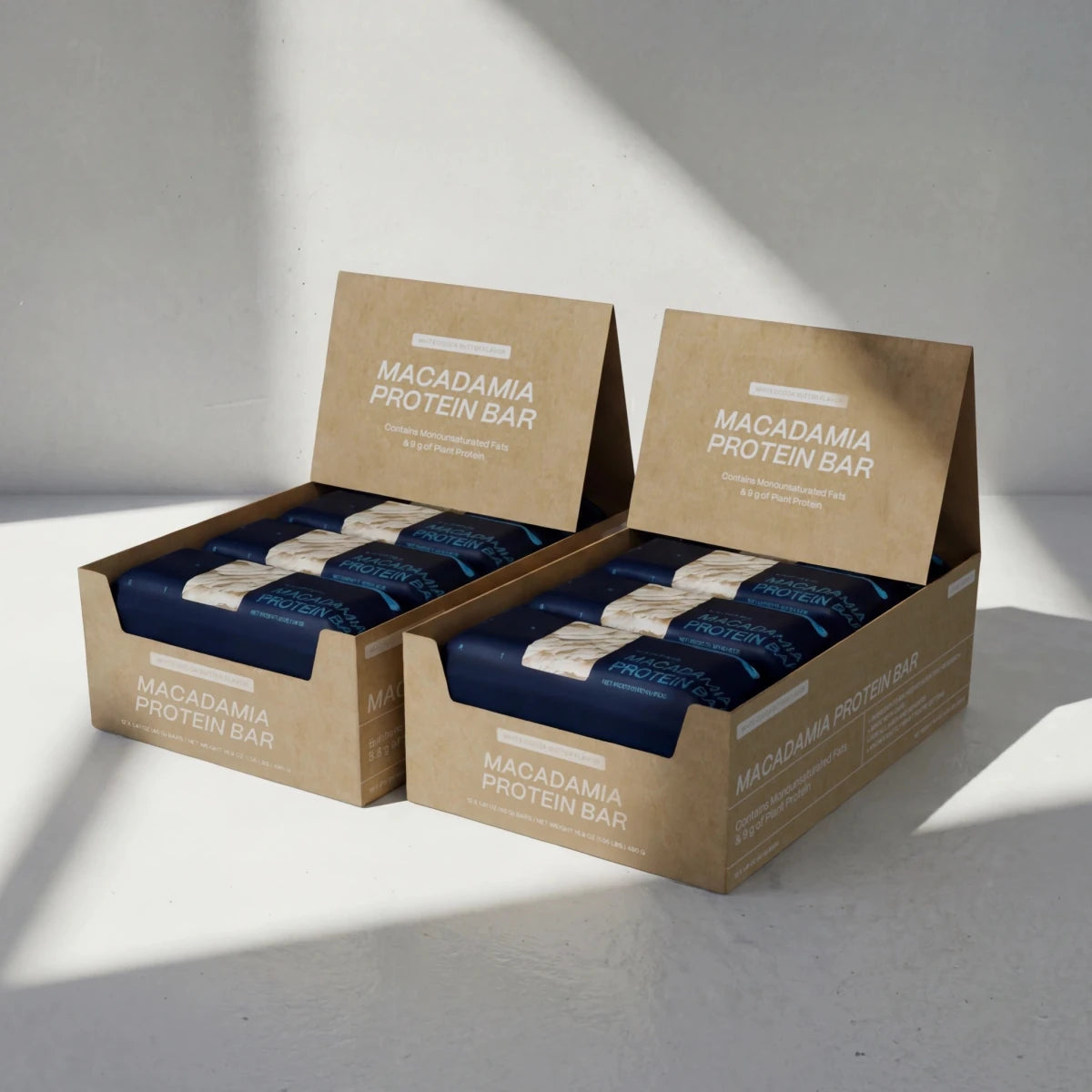 Two boxes of White Cocoa Butter Macadamia Protein Bars on a light gray background