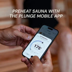 Person holding a smartphone with a temperature app open, preheating a sauna with the Plunge mobile app.