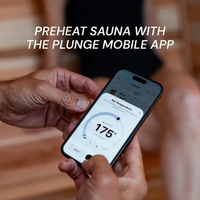 Person holding a smartphone with a temperature app open, preheating a sauna with the Plunge mobile app.