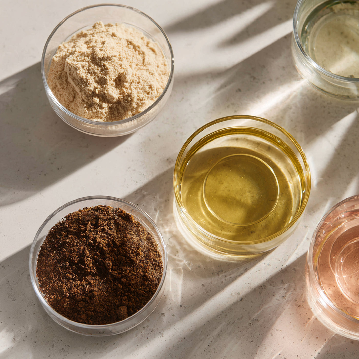 Four glass bowls containing different substances on a light surface