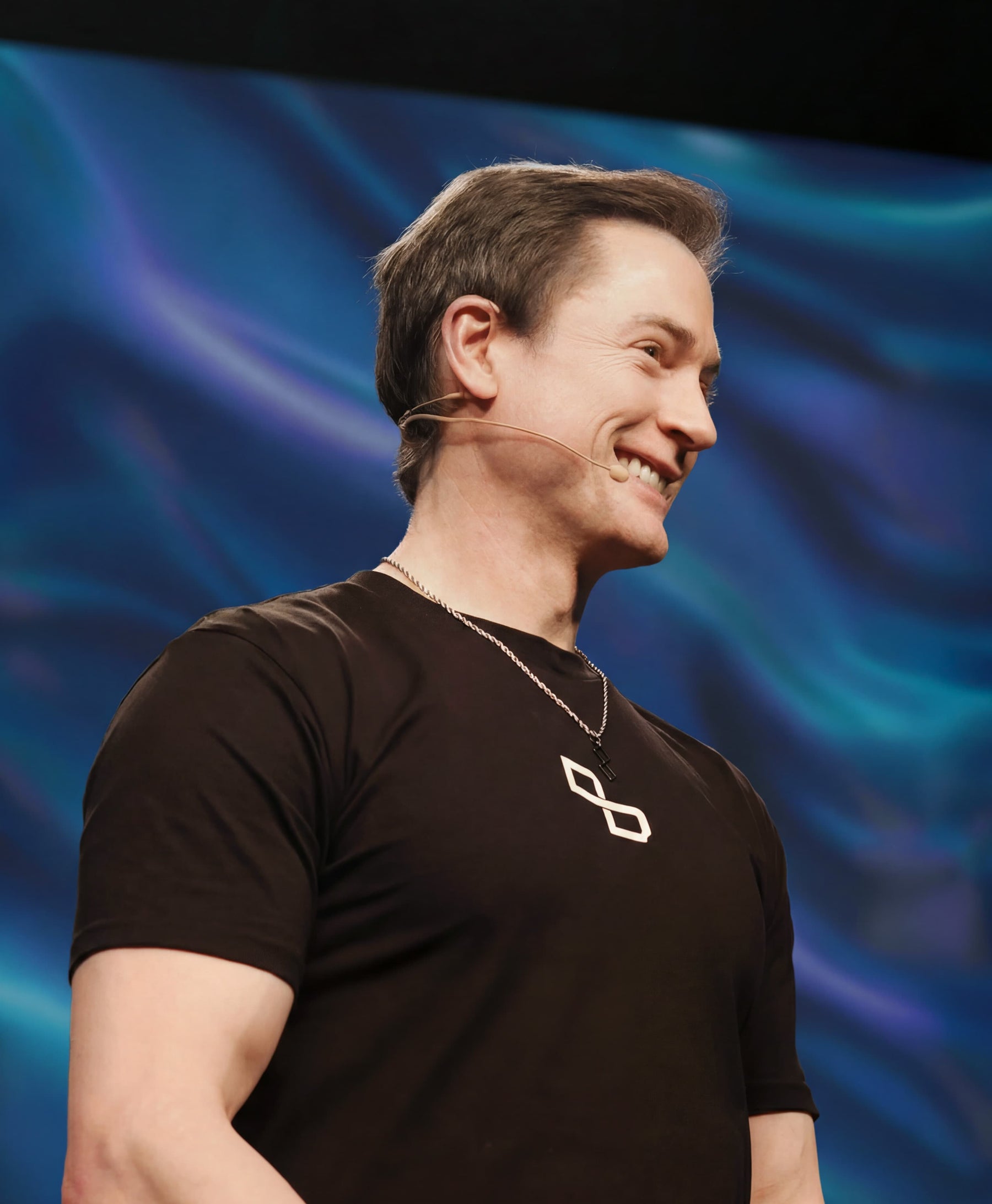 Bryan Johnson smiling on stage with blue abstract background